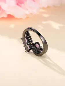 Detail shot of black plated irregular ring featuring sparkling purple zircon stones