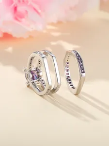 Gedetailleerde close-up van een driedelige ringenset met paarse steen en zilveren laag