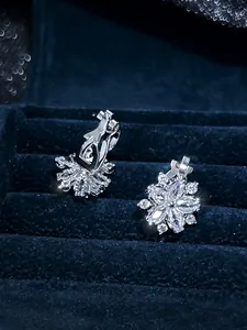 Macro shot of silver snowflake earrings with clear zircon stones on navy velvet