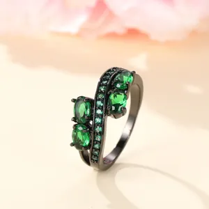 Irregular black metal ring with four green oval stones and pave-set green cubic zirconia