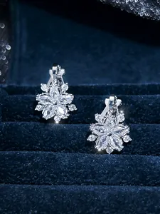 Detailed view of silver flower earrings with white crystals on a navy velvet jewelry box