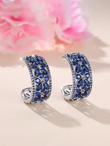 Détail de boucles d'oreilles C argentées serties de zircons bleu foncé marquise
