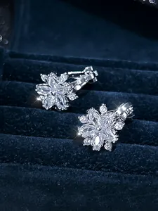 Macro view of silver floral clip earrings with crystals on navy velvet jewelry box