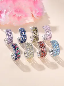 Détail de boucles d'oreilles créoles argentées serties de zircons colorés marquise