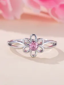 Macro shot of silver flower ring featuring pink round-cut gemstone and hollow petals