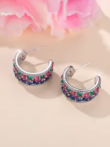 Détail macro de boucles d'oreilles créoles en C avec zircons colorés marquise