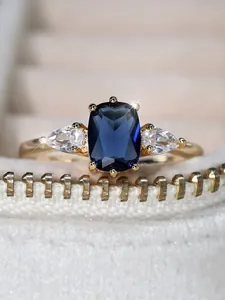 Gros plan d'une bague saphir avec pierres latérales dans un coffret à bijoux