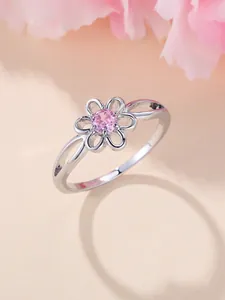 Detailed view of hollow flower ring with pink zircon on soft petal background