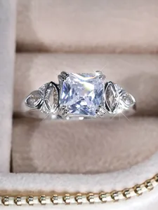 Macro shot of princess cut square stone with side teardrop gems on a velvet jewelry box