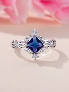 Dettaglio macro dell'anello con zaffiro blu quadrato, incisioni in argento e diamanti bianchi