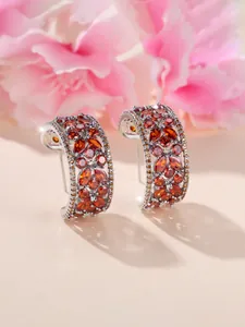 Vue macro des boucles d'oreilles créoles argentées avec zircons orange marquise