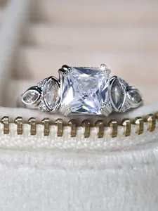 Macro detail of silver ring with princess cut center stone and marquise side accents