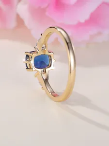 Vue latérale détaillée d'une bague saphir dorée avec pierre rectangulaire et diamants