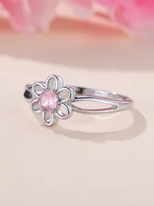 Detailed side view of silver ring featuring a floral镂空 setting with pink gemstone