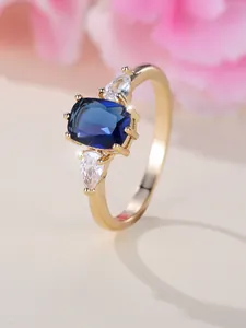 Détail d'une bague saphir bleu taille coussin avec pierres latérales en goutte sur or