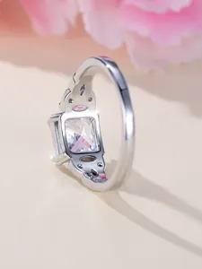 Detail view of square white gemstone ring with hollowed patterns and side diamonds