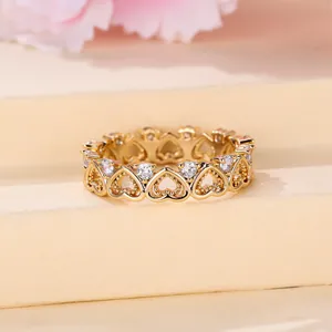 Detail of gold hollow heart ring with sparkling zircons on a floral background