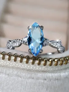 Macro detail of marquise cut light blue gemstone and twisted silver ring band with diamonds