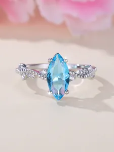 Macro shot of marquise-cut blue gemstone and twisted silver ring band with diamonds