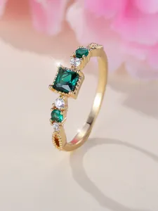 Macro-opname van gouden ring met vierkante smaragdgroene steen en diamantaccenten