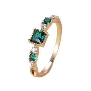 Elegante gouden ring met vierkante smaragd en fonkelende zijstenen op een witte achtergrond