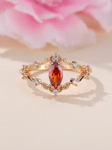 Detailaufnahme des champagnergoldenen Rings mit orangefarbenem Marquise-Stein und Blättern