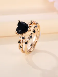 Macro view of vintage gold rings set featuring black heart gem and vine leaf details