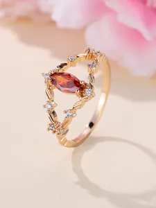 Detaillierte Nahaufnahme von Champagnergoldring mit Marquise-Granat und Blattmotiv