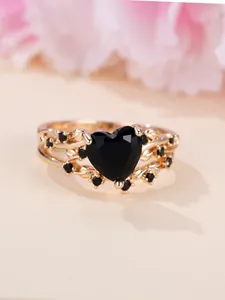 Macro view of a heart-shaped black zircon ring with rose gold vine band and micro-inlays