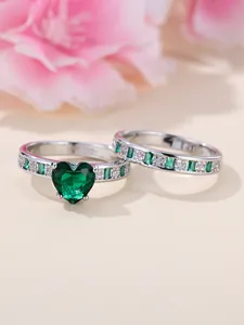 Macro view of heart-shaped emerald ring set with white diamonds and silver band