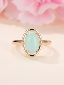 Detailaufnahme von ovalem grünen Stein gefasst in champagnerfarbenem Ring mit Roségold