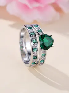 Detail of silver rings set with heart-shaped emerald stone and crystal accents