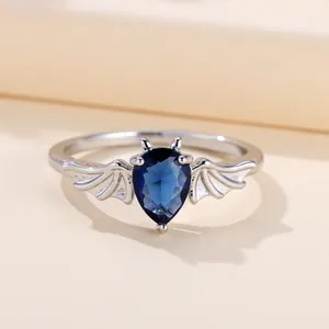 Anello con ali di pipistrello in argento e gemma blu a forma di pera su uno sfondo chiaro
