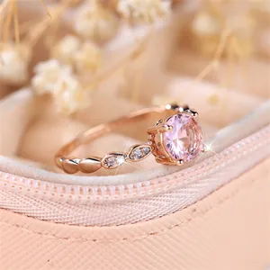 Detail of rose gold ring featuring a round pink gemstone and drop-shaped zircon accents