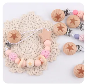 Detail of baby pacifier clip with beech wood star, silicone beads and knit textures