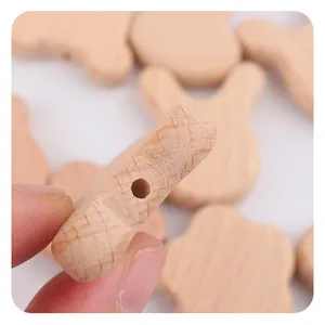 Detailed view of beech wood baby teether with pre-drilled holes and engraved patterns