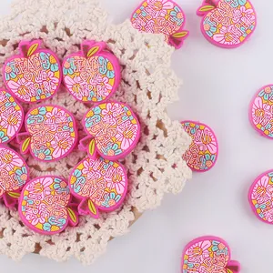Mordedor de silicona rosa con forma de manzana y flores sobre un tapete trenzado