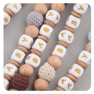 Macro view of baby pacifier clip featuring natural wood, crochet beads, and baby letters