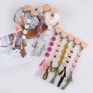 Detail of handmade woven pacifier clips with wooden heart buckles and cotton tassels