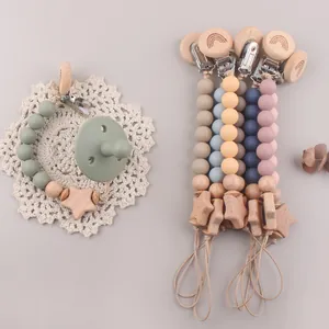 Detail of beech wood pacifier clip with silicone beads and star accent on lace mat