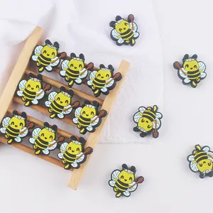 Detail of yellow silicone bee beads with daisy flower and honey dipper on white cloth