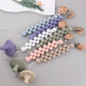 Colorful silicone and beech wood baby pacifier clip set with beads on a neutral background