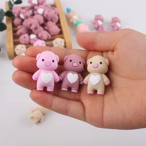 Handheld display of cute 3D silicone pig beads for baby teether DIY in pink colors