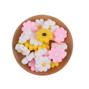 Daisy flower silicone beads in pink yellow and white colors inside a wooden bowl