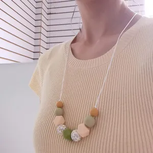 Detail of floral printed silicone beads on a minimalist nursing necklace worn by a model