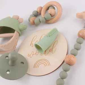 Detailweergave van siliconen dinosaurus bijtringset met fopspeen en houten kralen