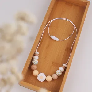 Detailed macro view of daisy silicone teething necklace with wooden beads in a bamboo tray