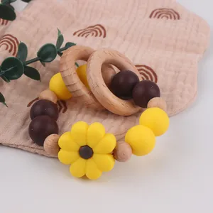 Detail of wooden baby rattle with sunflower silicone bead and natural rings on cotton fabric