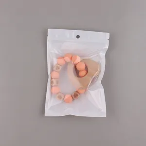 Baby teething ring set with silicone beads and heart wood pendant in clear retail packaging