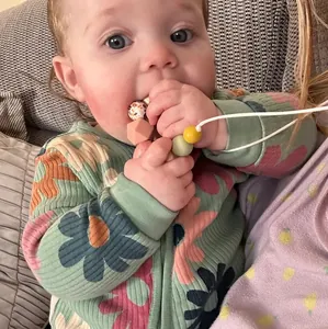 Baby chewing on colorful silicone teething necklace with various beads and patterns